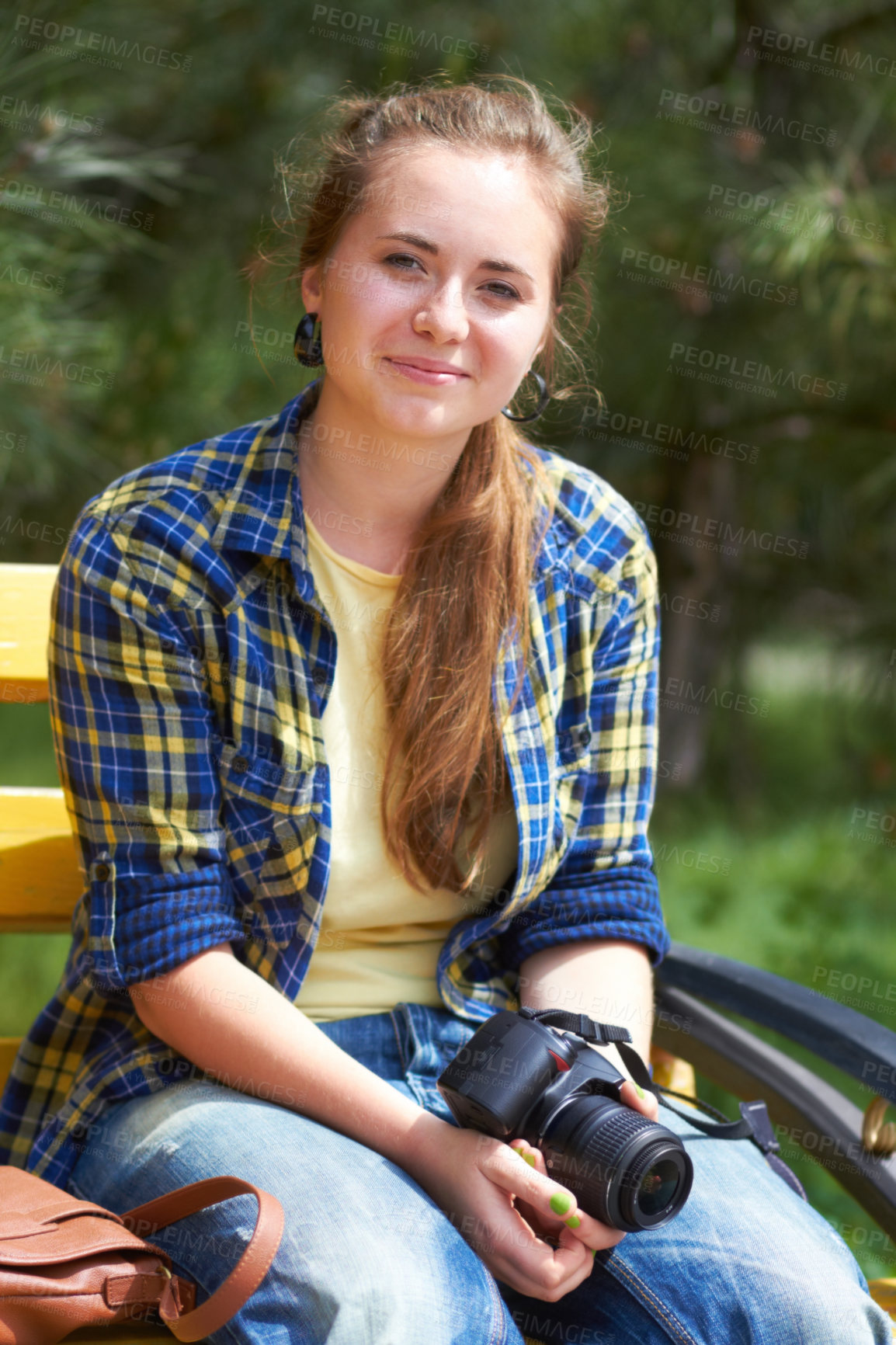 Buy stock photo A gorgeous young woman sitting in a park holding her camera