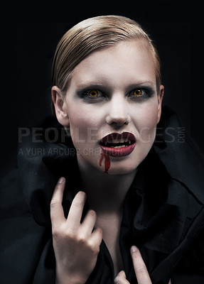 Buy stock photo A provocative female vampire with blood running down her chin against a dark background