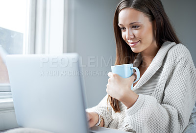 Buy stock photo Attractive young brunette sipping coffee while sitting at home in front of her laptop