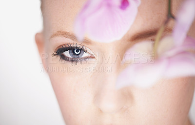 Buy stock photo A beautiful young woman looking out from behind an orchid