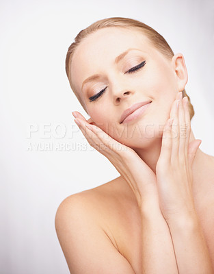Buy stock photo Shot of a pretty young woman touching her face against a gray background