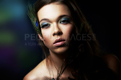 Buy stock photo Portrait, makeup and peacock feather with a woman in studio on dark background for natural skincare or wellness. Face, skin or beauty and a confident young model looking creative with cosmetics
