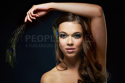 Buy stock photo Portrait, skincare and peacock feather with a woman in studio on dark background for natural skin or wellness. Face, beauty or makeup and arm of a young model looking creative with artistic cosmetics