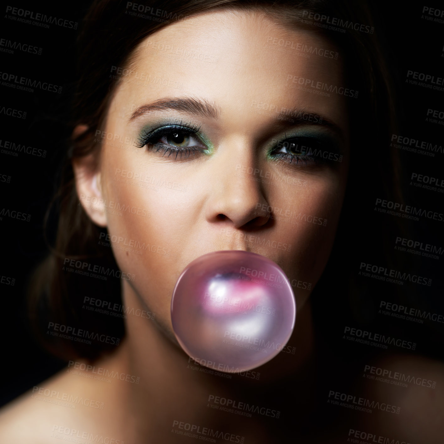 Buy stock photo Shot of a young woman blowing a bubble with her gum against a dark background