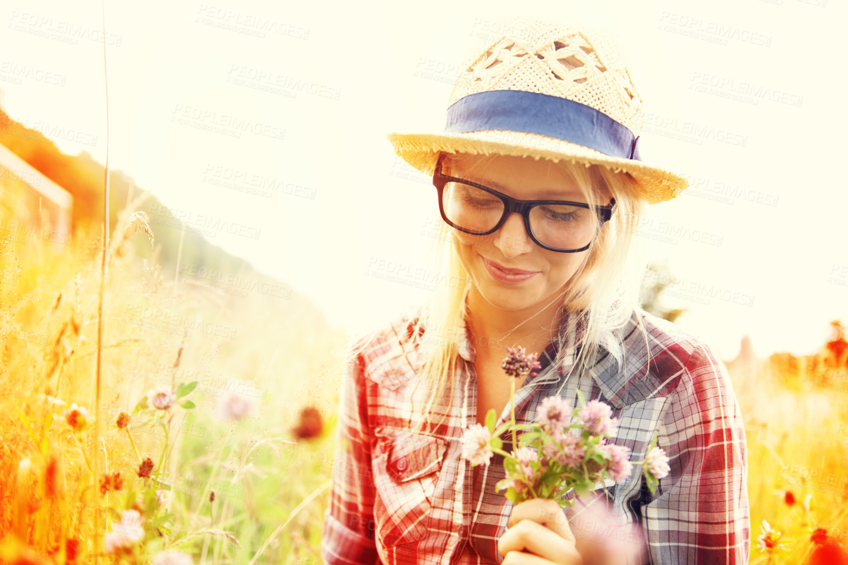 Buy stock photo Lens flare, countryside and woman with flowers in field for freedom, wellness and fresh air outdoors. Nature, summer and happy female person in natural meadow for relaxing, calm and peace in morning