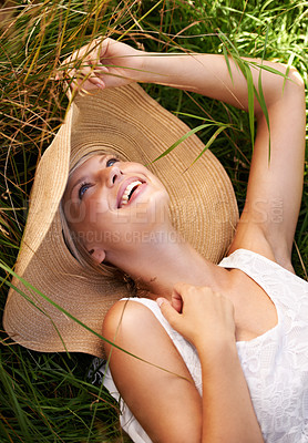 Buy stock photo Summer, hat and woman relax on grass with happiness and freedom in nature. Outdoor, fashion and girl lying on lawn with a smile on face for holiday, vacation or free time in meadow with wellness