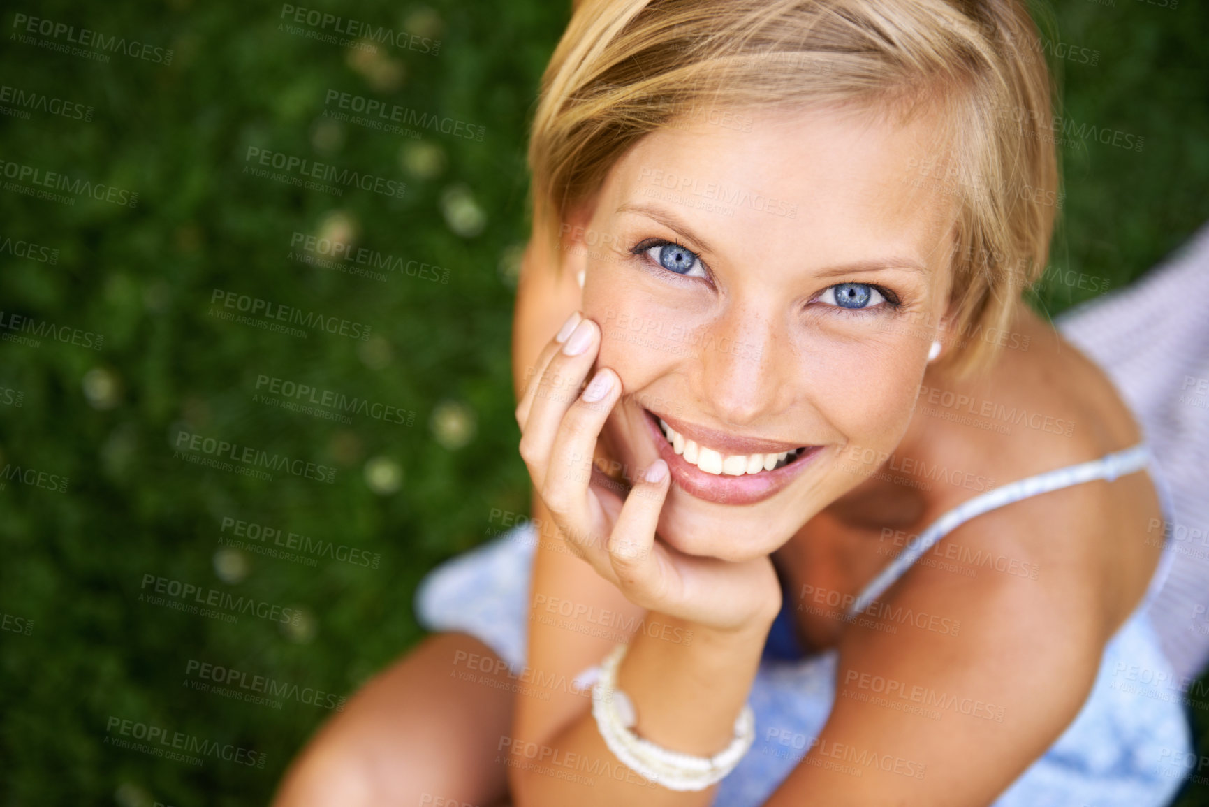 Buy stock photo Attractive young blonde woman sitting and smiling on the grass outside