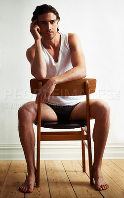 Buy stock photo Sexy, portrait of young man on chair by white wall with underwear for strong, body building and hot muscles. Serious, attractive and handsome male model posing with confidence on wood stool with vest