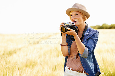 Buy stock photo An attractive young woman holding a camera while out in a field