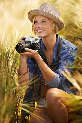 Buy stock photo Field, summer and woman with a camera, photographer and sunshine with tourism, travelling and picture. Person, photography or girl with nature, thinking or countryside with freedom, smile or creative