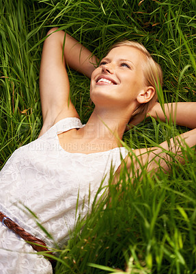 Buy stock photo An attractive young woman lying in an open green field
