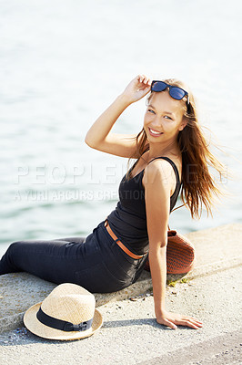 Buy stock photo A young woman sitting with her feet in the water at the harbour