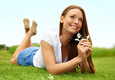 Buy stock photo Thinking, smile and woman with daisy on grass, lying down on field and enjoying spring on vacation outdoor. Happy, flower plant and beauty of female person relaxing, smiling and having fun in nature.