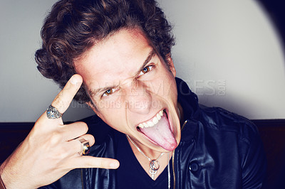 Buy stock photo Rockstar man, horns and hand in studio for emoji in spotlight, fashion or leather jacket by background. Person, symbol and icon by halo for portrait, punk style and tongue with jewelry for aesthetic