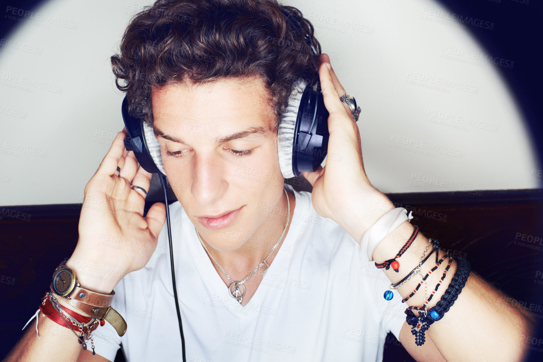 Buy stock photo Close up shot of a young man grooving to some music on a set of headphones surrounded by a halo of light