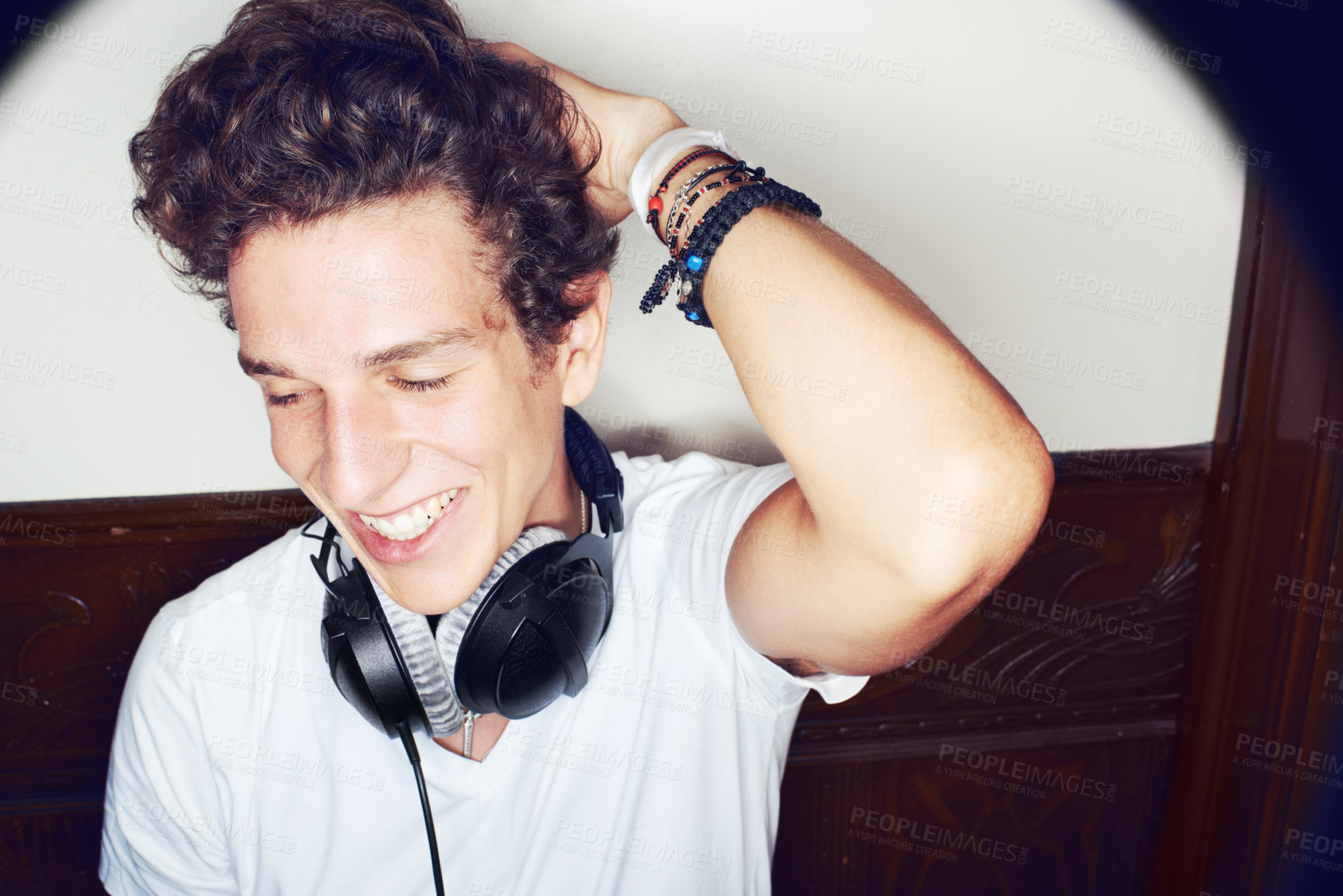 Buy stock photo Shot of a stylish young man wearing headphones around his neck and running his hands through his hair