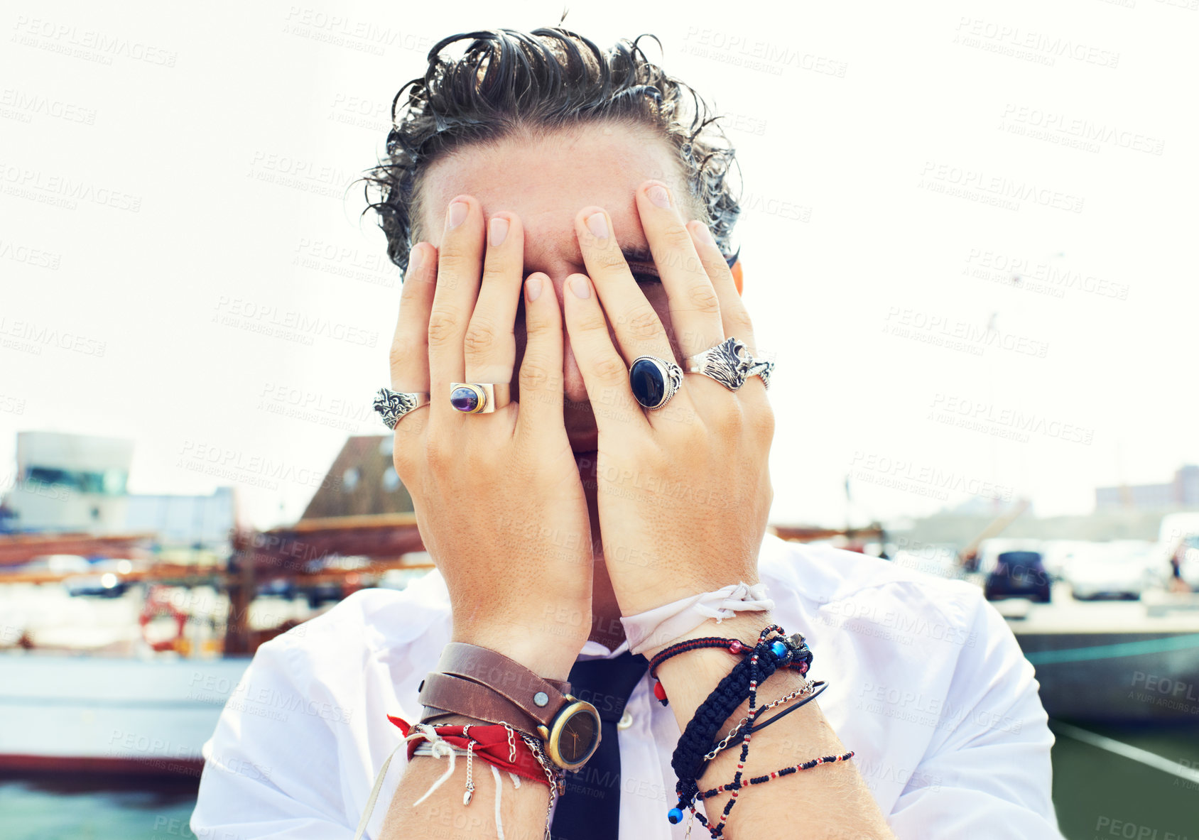Buy stock photo Hands, rings and accessories with a man in in the harbor by the sea for fashion or style. Jewelry, bracelet and fingers on the face of a young person for trendy or edgy expression by the pier