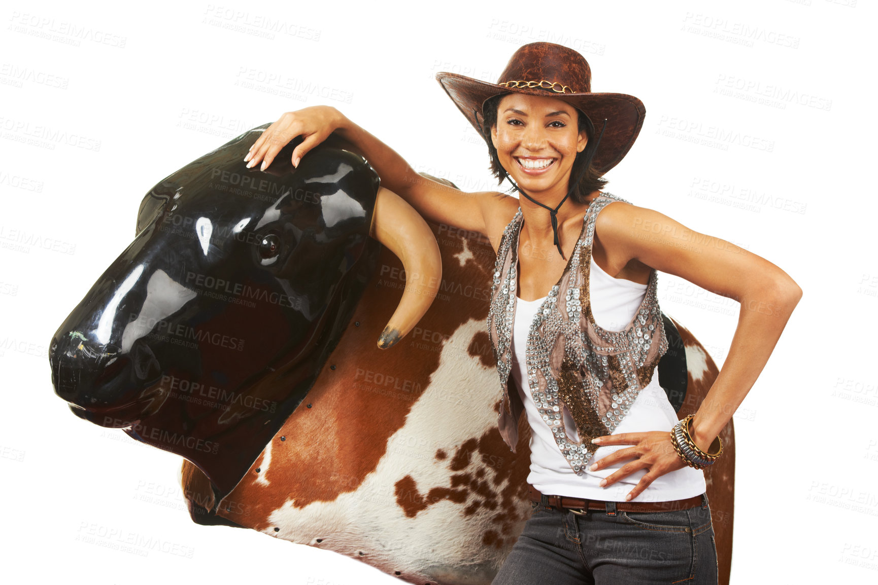 Buy stock photo Studio shot of a beautiful young cowgirl standing next to a mechanical bull against a white background