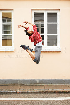 Buy stock photo An energetic young woman in urban sportswear jumping in the street