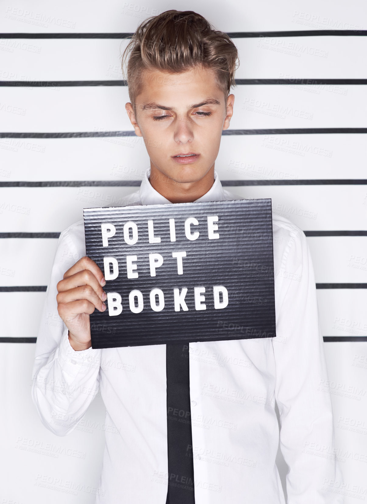 Buy stock photo Mug shot of a young man in a shirt and tie holding up a police department sign