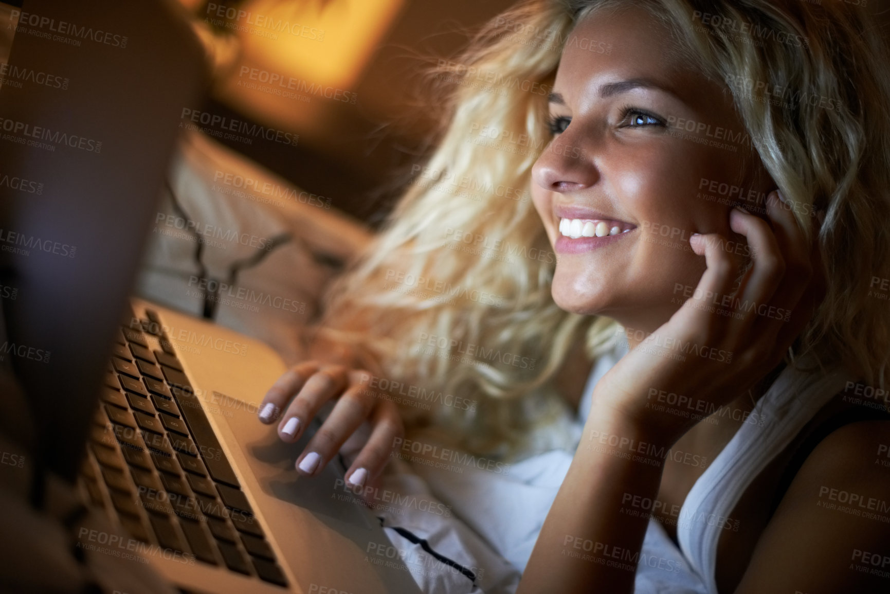Buy stock photo Shot of a young woman using her laptop on her bed at night