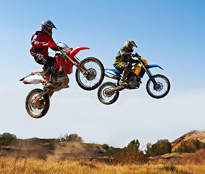 Buy stock photo Action shot of two dirt bikers jumping with their bikes over a field