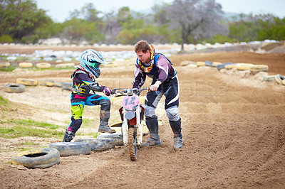 Buy stock photo Motorcycle, child and father help on dirt road, training and outdoor sports. Bike, kid and dad coaching rider, teaching and learning together at race, competition and mentor support on transportation