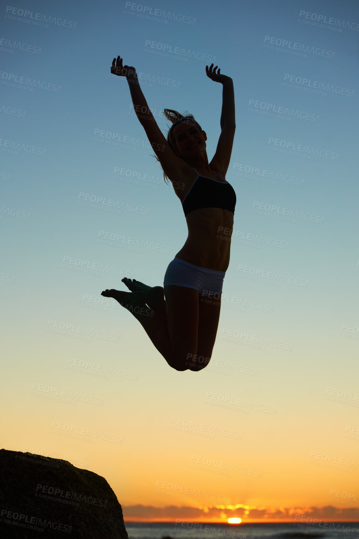 Buy stock photo Silhouette of a young woman jumping in the air at sunset
