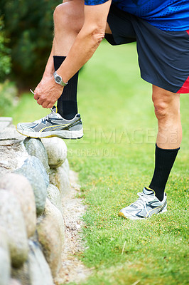 Buy stock photo Fitness, tie or runner with shoes on rock by nature for exercise, training or outdoor workout. Hands, man or closeup of legs of athlete in park with sports footwear ready for jog, walking or wellness