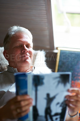 Buy stock photo Relax, magazine or senior man reading newspaper articles in home for information or story updates. Smile, book or mature person studying abstract art for knowledge in a publication in living room