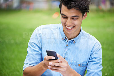 Buy stock photo Man, phone and smile for text in conversation, communication and chatting in outdoors on grass. Happy male person, laugh and joy at funny message on smartphone, tech and notification on social media