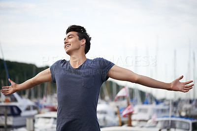 Buy stock photo A young man with arms outstretched relishing the breeze