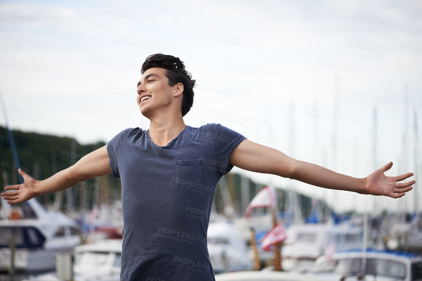 Buy stock photo A young man with arms outstretched relishing the breeze