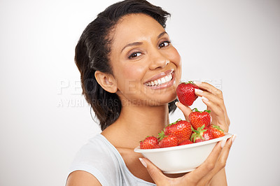 Buy stock photo Happy, strawberries and portrait of woman in a studio for wellness, nutrition and organic diet. Smile, vitamins and young female person eating a fruit for healthy vegan snack by gray background.