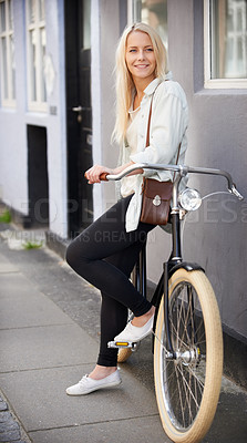 Buy stock photo A beautiful young woman leaning on her bike on the side of the street