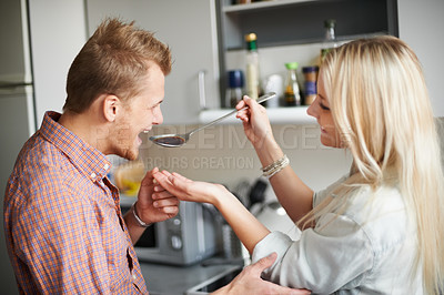 Buy stock photo Cooking, love and couple with taste test in a kitchen happy, hungry and bonding in their home together. Food, sample and people in a house for feeding, fun and meal prep, brunch or dinner on weekend