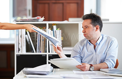 Buy stock photo Shot of a mature office worker receiving a stack of work while sitting at his desk