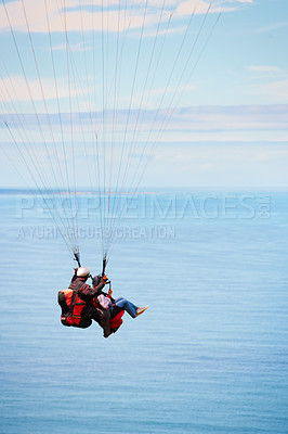 Buy stock photo Sky, ocean and air with a couple in a parachute together for travel, freedom or adventure. Sea, summer or nature with a man and woman flying over the water while bonding on holiday or vacation