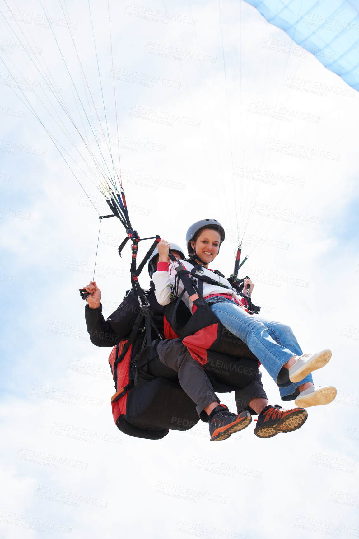 Buy stock photo People, paragliding and smile in sky, together or extreme sport with freedom for fitness. Coach, partnership and person on adventure, helmet or fearless with backpack, parachute or portrait in clouds