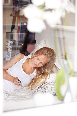 Buy stock photo Young woman lying in bed and listening to her mp3 player