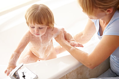 Buy stock photo Cropped shot of a mother washing her baby girl in the bathtub