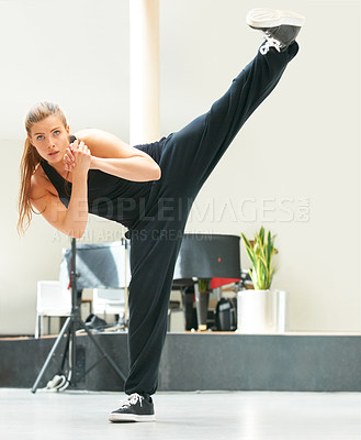 Buy stock photo A young dancer kicking her leg into the air while rehearsing a dance routine