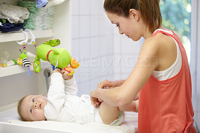 Buy stock photo Young mom finishing dressing the baby boy