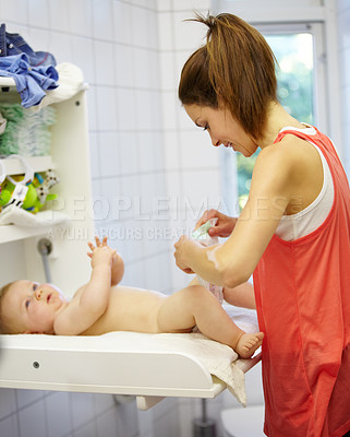 Buy stock photo Cute young mom changing a baby's diaper