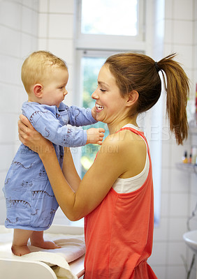 Buy stock photo Mother, holding and baby for dressing in home on changing table for future, growth or development. Young woman, infant and playful in morning with smile of face for child, curiosity and motor skills