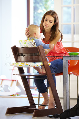 Buy stock photo Woman, baby and food in feeding chair for nutrition, growth and development at table in kitchen of home. Mother, infant and cleaning face after eating, napkin and routine for love, care and nurture