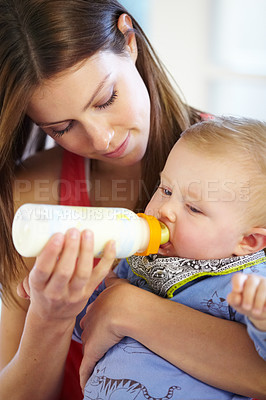 Buy stock photo Mother, baby and holding with bottle in home of formula, feeding or hunger for future growth. Woman, infant or son with nutrition for child development, milestone and health in kitchen with bonding
