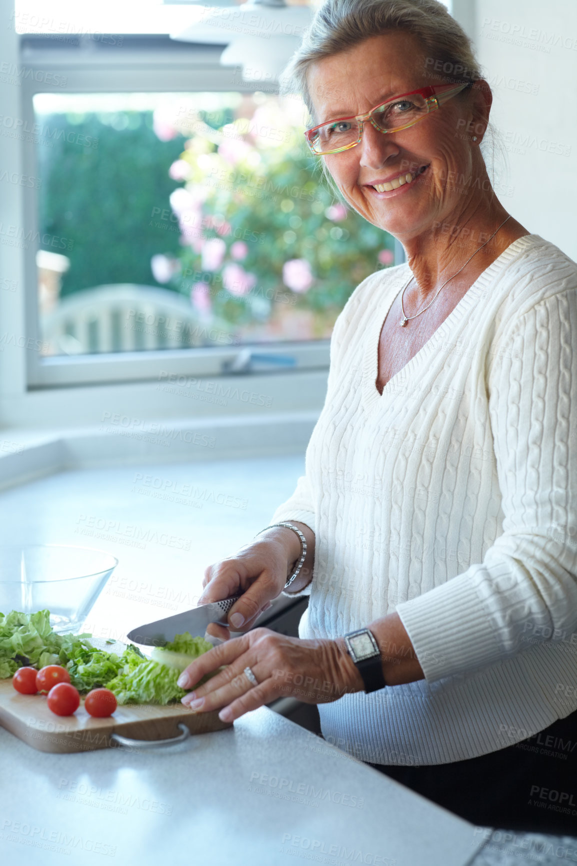 Buy stock photo Portrait of senior woman on chopping board, vegetables and knife in kitchen cooking food. Happy person in glasses cutting plants on counter, lettuce and tomatoes, nutrition and healthy diet in home