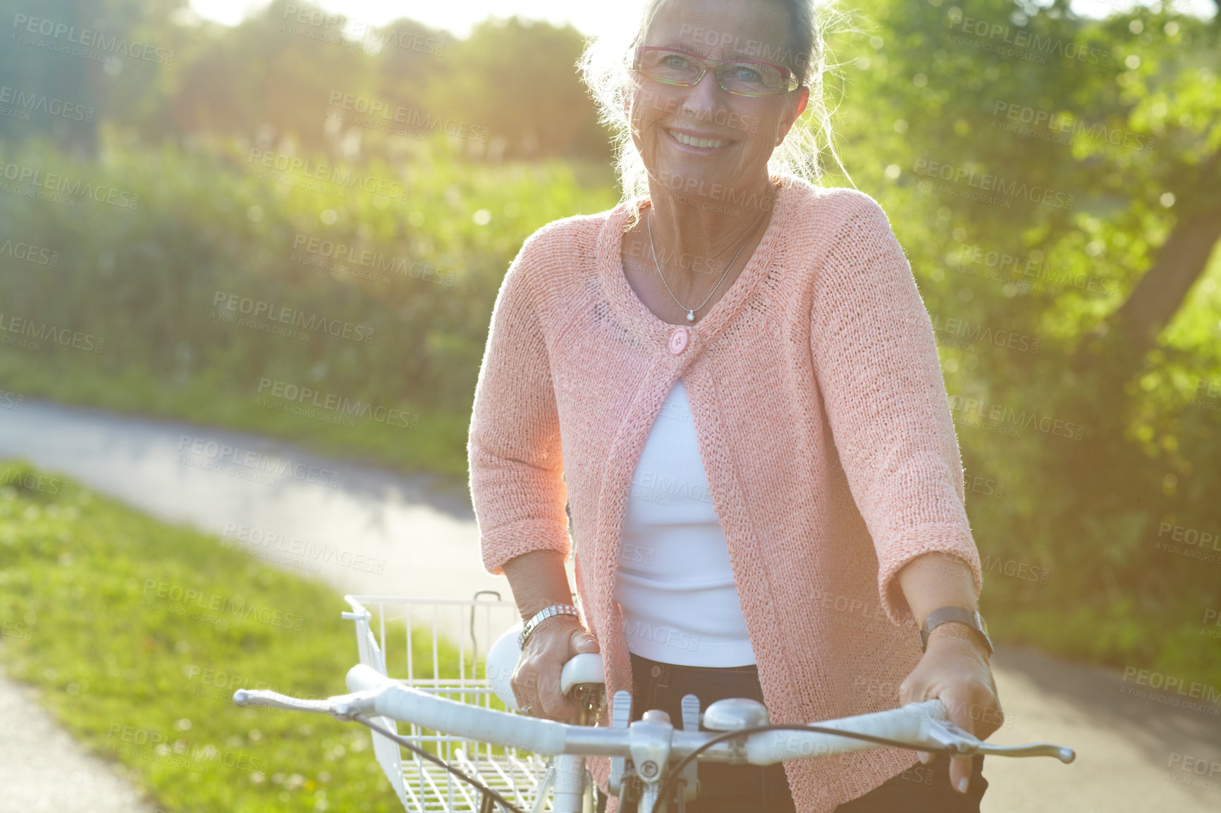 Buy stock photo Portrait, smile and elderly woman on bike outdoor, exercise and fitness in summer. Happy, senior person on bicycle in nature or garden for cycling in countryside for body health, travel and glasses