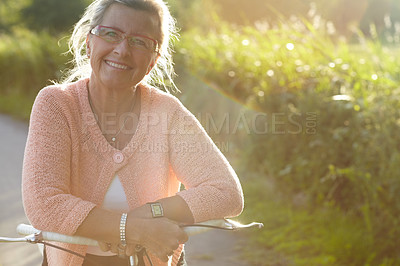 Buy stock photo Portrait, senior and happy woman on bicycle in nature for exercise, wellness and health outdoor. Face, smile and elderly person on bike, glasses at park and cycling in garden or summer countryside